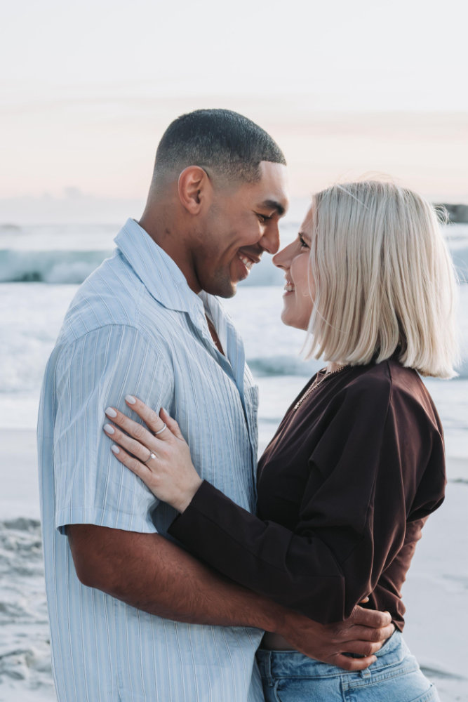 A newly engaged couple embracing on the beach
